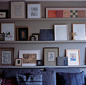 Picture display of watercolours Persian miniatures and drawings on shelves lining the living room walls