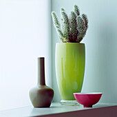 Still life of brightly coloured ceramic vases with cactus on a windowsill in a modern whitish green bedroom