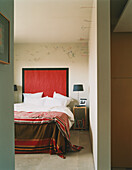 Blick auf ein farbenfrohes, modernes Schlafzimmer vom offenen Wohnbereich aus