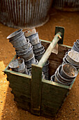 Stack of small zinc pots in a wooden trug in a greenhouse