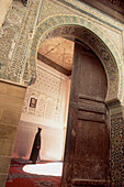 Man in djellabah standing in grand ornate entrance hall