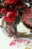 Detail of colourful red flower bouquet in a ceramic vase on a floral embroidered tablecloth