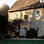 Exterior of period country house with arched windows and door with stone walls