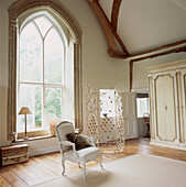 Living room with wood floor beams and large arched window in neutral colours