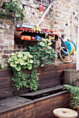 Walled brick garden with wooden bench with storage space inside and shelving on the garden wall for toys