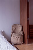Abgenutzter Pappsessel in einem modernen Schlafzimmer mit Trennwänden