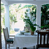 Outdoor dining area shaded from the sun with the table dressed in cool linen ready for lunch