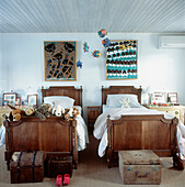 Children's bedroom with mahogany twin beds piled with soft toys ad a fish mobile