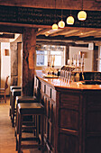 Bar of a traditional public house with wooden bar stools and beer pumps 