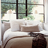 Schlafzimmer mit bestickten Kissen und Fenster mit Blick auf den Garten