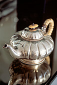 Vintage silver teapot on mirrored table