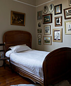 Antique single bed and artwork display in bedroom of London townhouse, UK