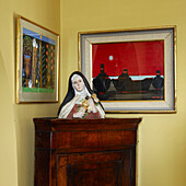 Corner of room, detail with artwork and a figurine of a nun
