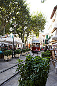 Straßenbahn fährt zwischen zwei Restaurants im Stadtzentrum auf Mallorca