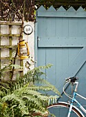 Bicycle on gate in yard with trellis and fern