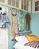 Vintage clothing hangs in light blue painted bedroom