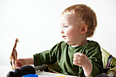 Zwei Jahre alter Junge in grünem Oberteil spielt mit Spielzeuggiraffe