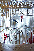 White decorative birdcage filled with christmas decorations close up