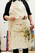 Woman holding paint brush in Artists apron