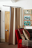 Living room entrance doorway with draft excluder curtain and sofa with rugs and cushions