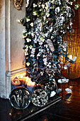 Detail of fireplace with festive garland and candles and glass paperweights on the hearth