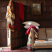 Kissen und Decken mit Bademantel und Sofa in einem getäfelten Zimmer in einem Londoner Haus, UK