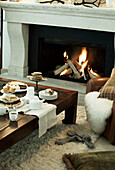 Tea and cake on table with lit fire in luxury Zermatt home, Switzerland