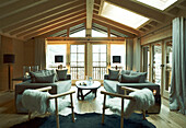 Matching sofa and chairs with coffee table in beamed living room of luxury Zermatt chalet, Switzerland