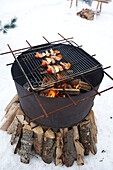 Kebabs on barbecue grill on open fire in snow, Zermatt, Valais, Switzerland