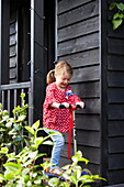 Junges Mädchen spielt auf einem Roller im Garten eines Londoner Stadthauses, England, UK