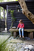 Mädchen sitzt allein im Garten eines Londoner Stadthauses, England, UK