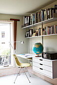 Desk space with bookshelves and globe in contemporary London home, England, UK