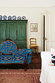 Upholstered antique sofa with green painted cabinet in old London townhouse, England, UK