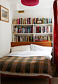 Checked blanket on double bed with books in London home, England, UK