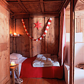 Festive Christmas decorations in red and white in a wooden chalet bedroom with burning candles