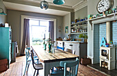 Wooden dining table with turquoise paintwork in open plan kitchen of family home in Rye, East Sussex, England, UK