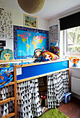 Bright blue platform bed with wall map in child's room of Hackney home, East London, UK