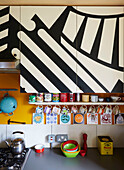 Black and white geometric pattern on fitted units above cup storage in Hackney kitchen, East London, UK