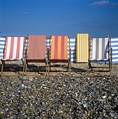 Striped deck chairs in row on pebble stone beach