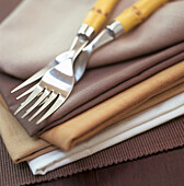 Beige and grey table linen with table forks on dark wood table
