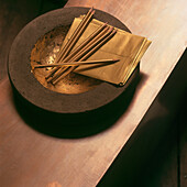 Close up of gold coloured stationery in gold leafed earthenware bowl 