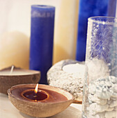 Display aus zerbrochenem Glas mit blauen Kerzen und Bienenwachskerzen