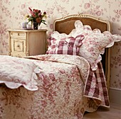 Floral bed linen on single bed in pink and white with matching wallpaper
