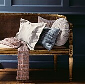 Woolen scarf on gilded sofa with cushions in contrasting shapes