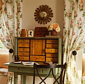 Antique writing bureau between floral curtained windows