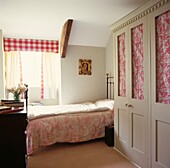 Single bed in room with glass fronted patterned wardrobes and sunlit window