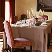 Esstisch mit rotkarierter Tischdecke, rot gepolsterten Stühlen und Vorhängen
