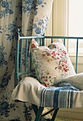 Blumengemustertes Kissen auf Tagesbett mit kontrastierenden Vorhängen