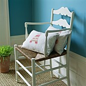 Cushions on painted armchair in turquoise room with high skirting board