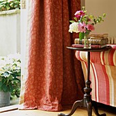 Russet floral patterned curtains at open door beside sofa